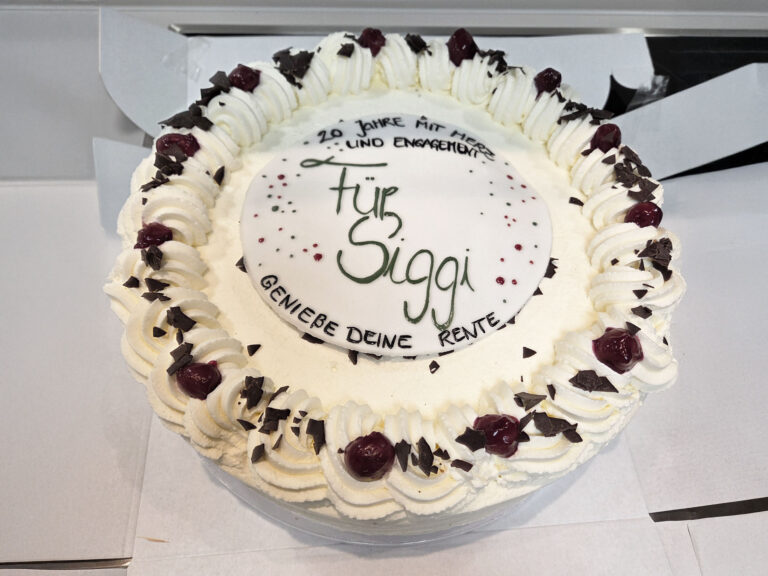 Torte mit Aufschrift „Für Siggi“ sowie „20 Jahre mit Herz und Engagement“ und „Genieße deine Rente“.