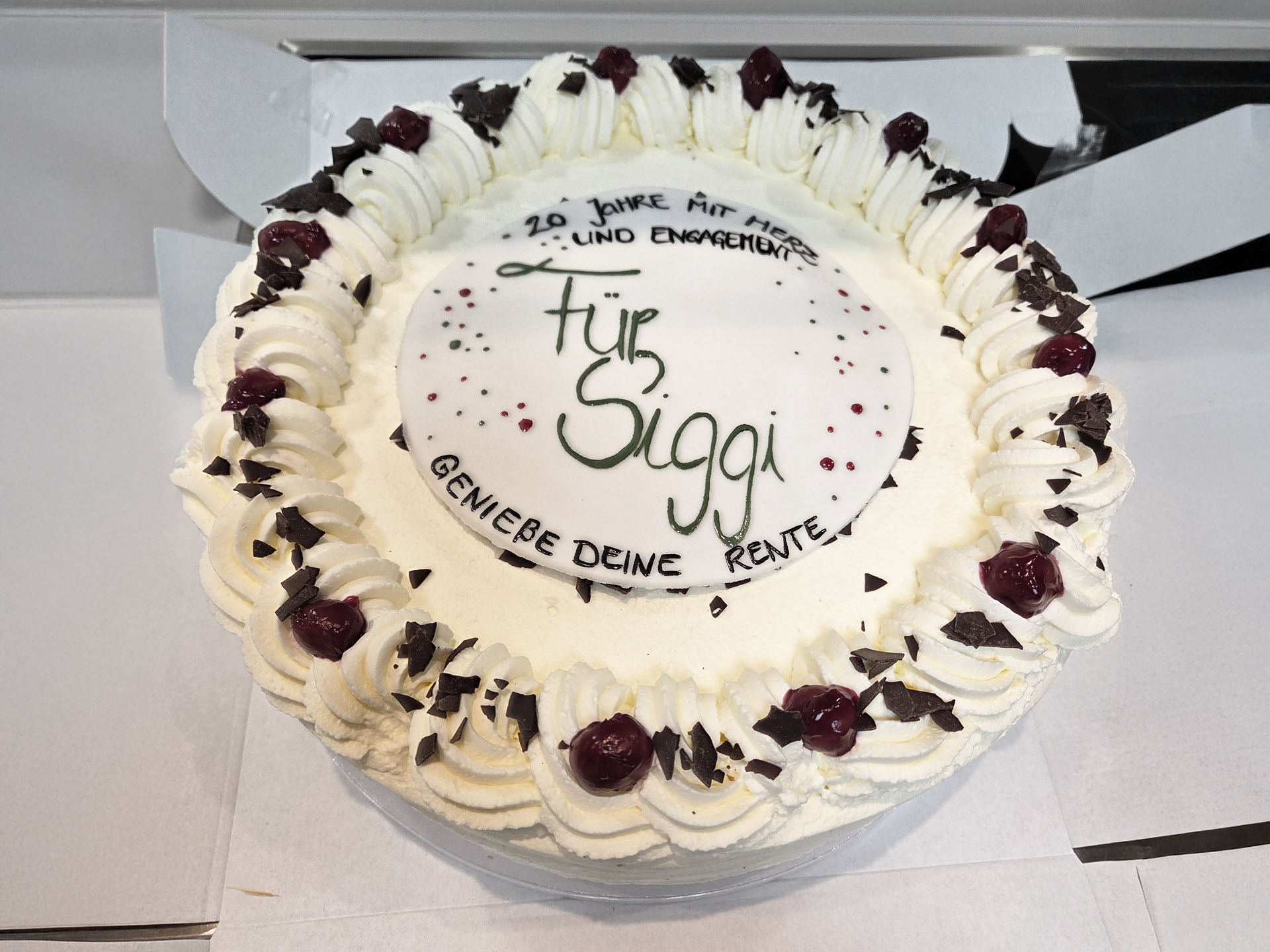 Torte mit Aufschrift „Für Siggi“ sowie „20 Jahre mit Herz und Engagement“ und „Genieße deine Rente“.